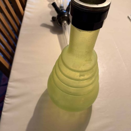 Gelbe Glasbowl für Shisha, auf Tisch mit Zubehör.