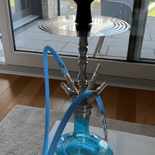 Blaue Shisha mit Glasbowl auf Tisch vor Fenster.