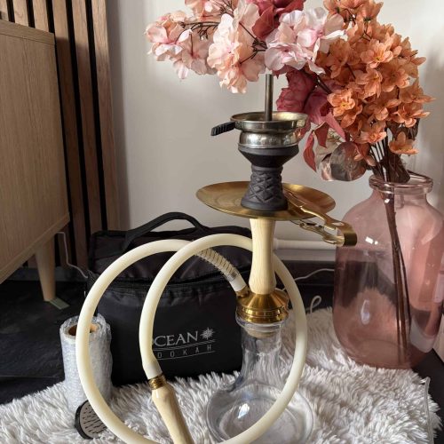 Shisha mit Blumen und Glasbowl auf Teppich, dekorativ und funktional.