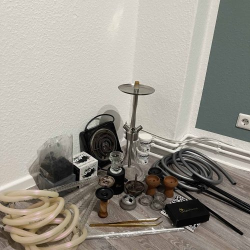 Verschiedene Shisha-Teile und Zubehör auf dem Boden.