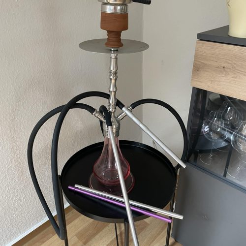 Rauchsäule mit Shisha-Setup auf einem schwarzen Beistelltisch, inklusive Schlauch und Tabak.