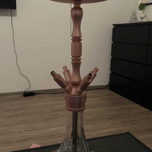 Shisha-Kopf mit Glasbowl und Zubehör, auf Tisch stehend.