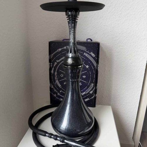 Shisha-Kopf mit schwarzer Glasbowl und Schlauch auf weißem Tisch.