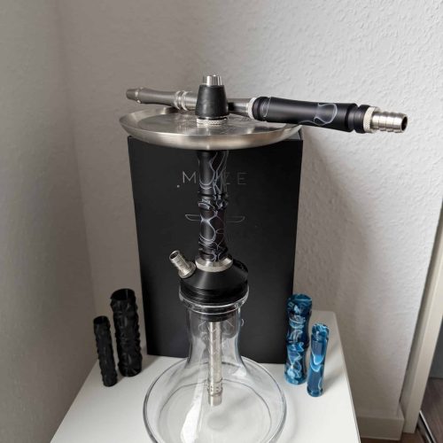 Shisha mit Glasbowl, Schlauch und Zubehör auf Tisch.