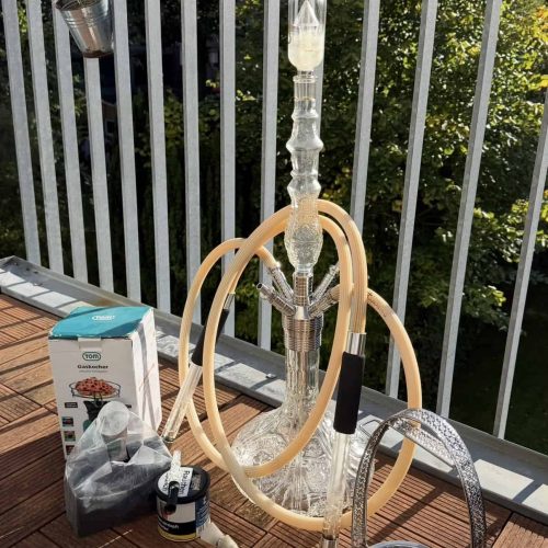 Shisha mit Glasbowl, Schlauch und Zubehör auf Balkon im Freien.