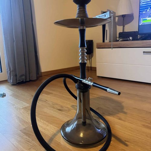 Shisha mit Schlauch, Tabakschale und Deko im Wohnzimmer.