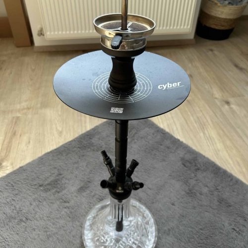 Shisha mit Glasbowl, Kopf und Schlauch auf Tisch.