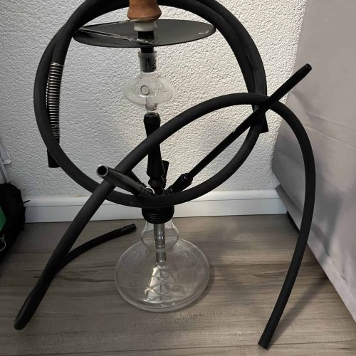 Shisha mit Glasbowl, Schlauch und Kopf, auf Boden stehend.