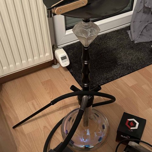 Shisha auf einem hohen Stand mit Zubehör im Wohnzimmer.