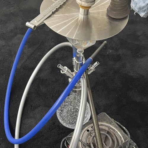 Shisha mit Glasbowl, Schlauch und Tabakkopf auf Tisch.