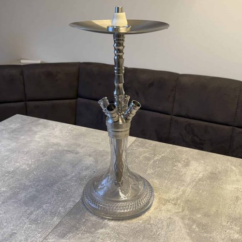 Elegante Shisha mit Glasbasis und Metallaufsatz, auf Tisch in Wohnzimmer.
