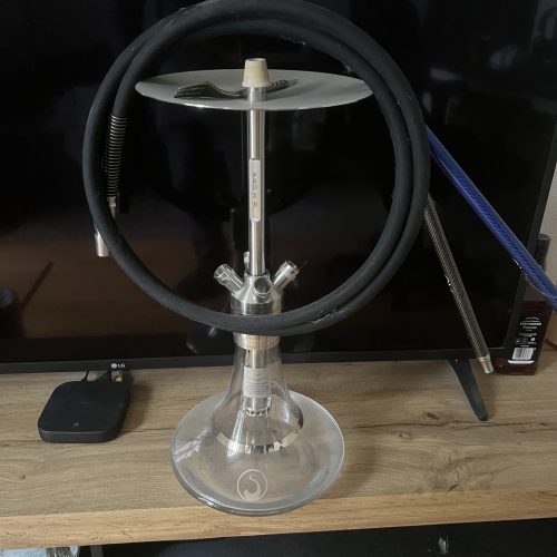Shisha mit Glasbowl, Schlauch und Metallstück auf Holz.