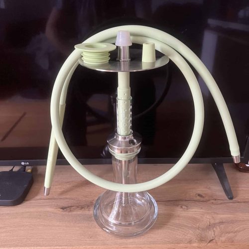 Shisha-Glasbowl mit Schlauch und Zubehör auf Tisch.