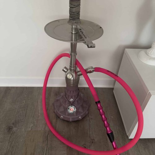 Rauchsäule mit pinkem Schlauch, Metallbasis und Glasaufsatz, ideal für Shisha-Genuss.