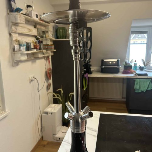 Rauchende Wasserpfeife auf einem Tisch, moderne Shisha in einem Wohnraum, ideal für Raucher und Samm.