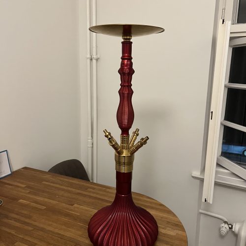 Roter Shisha-Kopf mit goldenen Anschlüssen auf Holztisch.