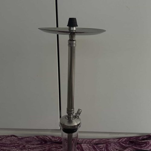 Shisha-Kopf mit Glasbowl und Schlauch auf lila Stoff.