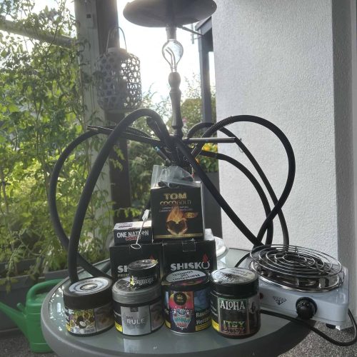 Shisha-Zubehör und Rauchsäule auf Balkon, Sonnenlicht im Hintergrund.