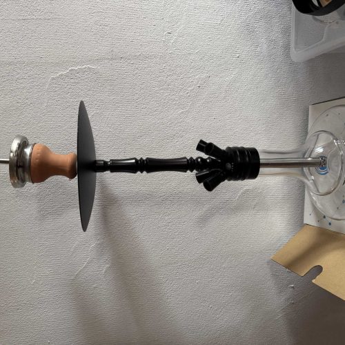 Shisha mit Glas und Zubehör, auf weißer Wand montiert.