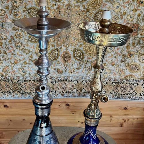 Zwei hochwertige Shishas mit goldenen und blauen Details vor einem Teppich.