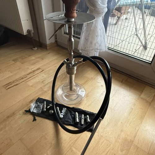 Shisha mit Rauchsäule und Zubehör im Wohnzimmer.