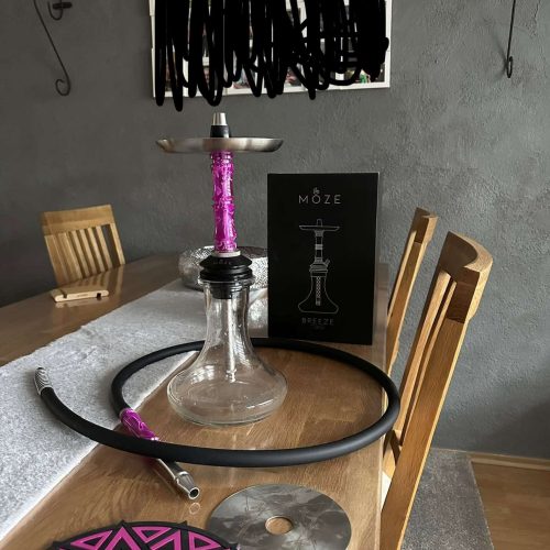 Shisha mit Glasbowl, Silikonschlauch und Zubehör auf Tisch.