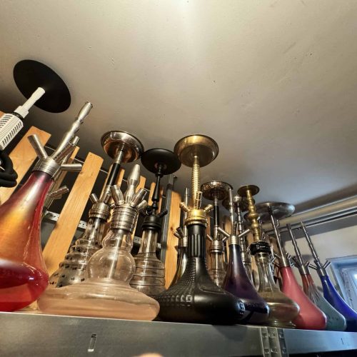 Verschiedene Shisha-Köpfe und Rauchpfeifen auf einem Regal.