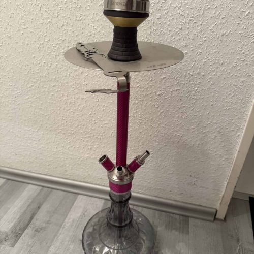 Shisha mit Glasbase, Tabak und Zubehör, auf einem Tisch.
