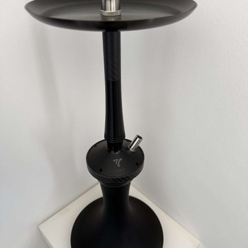 Moderne schwarze Shisha mit Glasaufsatz und Kohlezange, auf weißem Tisch.