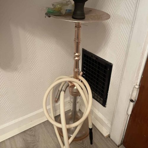 Shisha-Raucherset mit Schlauch, Tabak und Kohle auf kleinem Tisch.