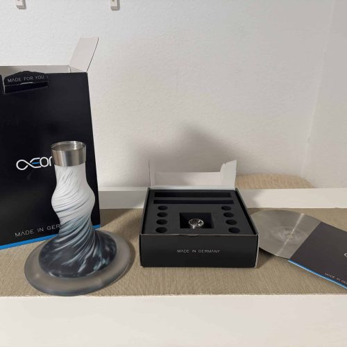 Moderne Shisha mit Glasbowl und Zubehör auf Tisch.