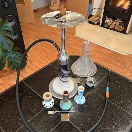 Shisha mit Glas- und Keramikzubehör auf schwarzem Boden.