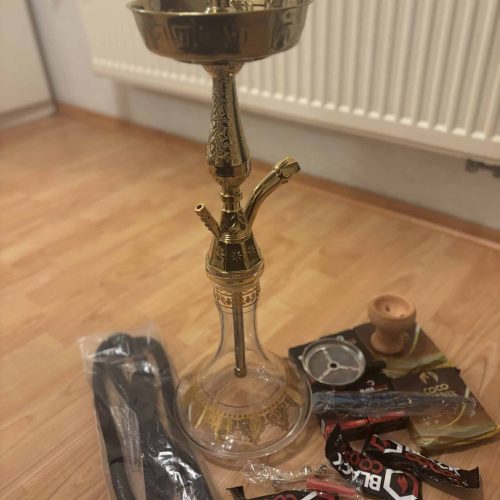 Goldene Shisha mit Glasbasis und Zubehör, auf Holzboden.