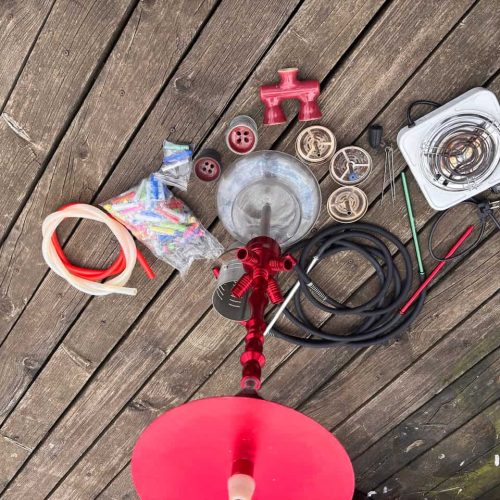 Verschiedene Shisha-Teile und Zubehör auf Holzterrasse.