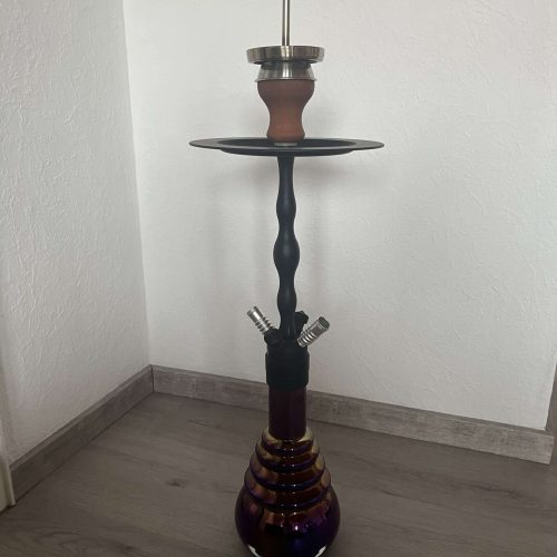 Wasserpfeife mit Zubehör, auf Boden stehend, gegen weiße Wand.