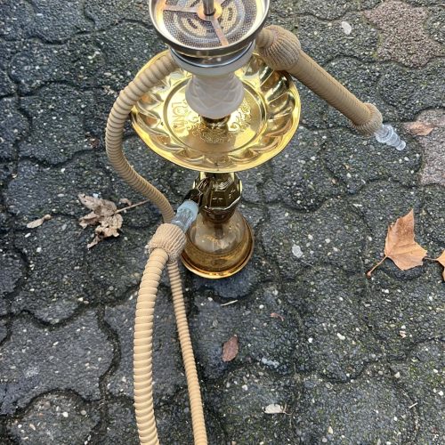 Shisha mit goldfarbenem Design und zwei Schläuchen auf Asphalt.