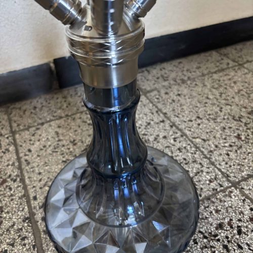 Moderne Shisha mit Metall- und Glasbestandteilen auf Fliesenboden.