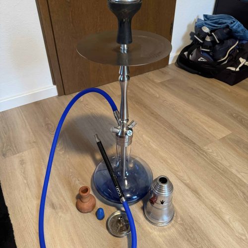Rauchsäule mit Shisha, Tabak und Zubehör auf Holzboden, ideal für gemütliche Raucherabende.