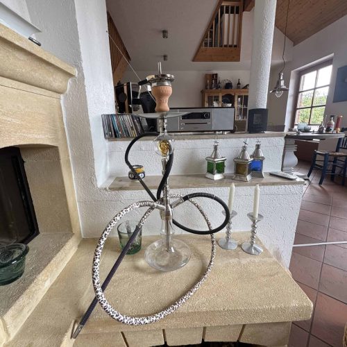 Shisha mit Schlauch und Kohle, dekorative Kerzen auf Kamin.