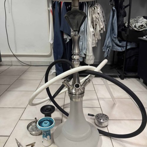 Shisha mit Schlauch, Tabak und Zubehör auf Boden.