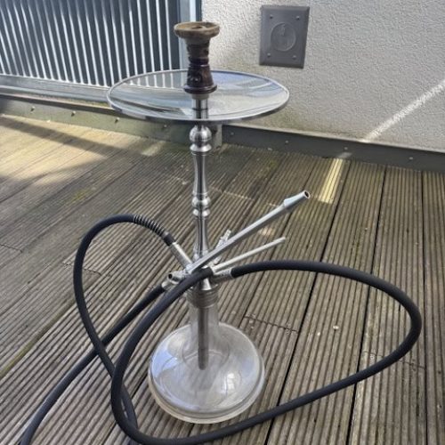 Shisha mit Glasbowl und Schlauch auf Holzterrasse.