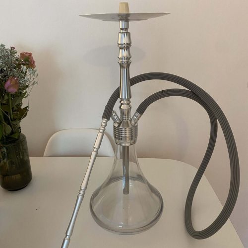 Shisha-Kopf mit Glasbowl, Schlauch und Metallrohr auf Tisch.