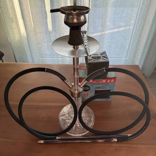 Rauchsäule mit Shisha-Set auf einem Tisch, inklusive Schlauch und Kohlehalter.