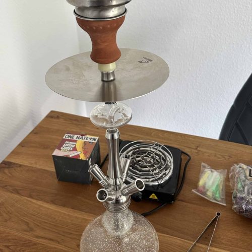 Shisha-Kopf mit Glasbowl und Metallrohr, auf Holztisch.