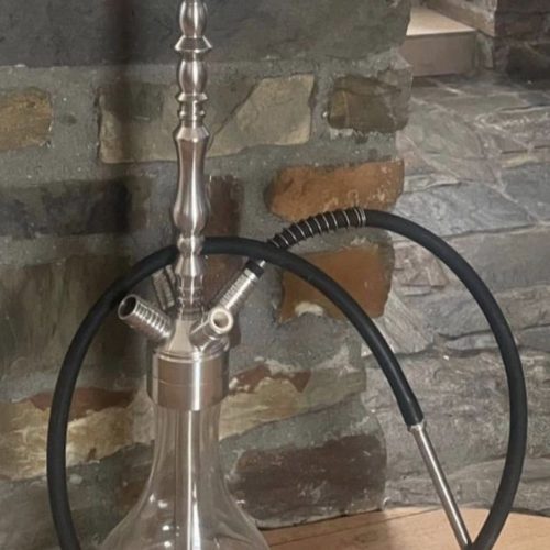 Shisha mit Glasbowl, Metallstange und Silikonschlauch auf Holztisch.