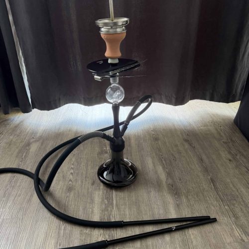 Shisha mit Glasbowl, Schlauch und Zubehör auf Holzboden.