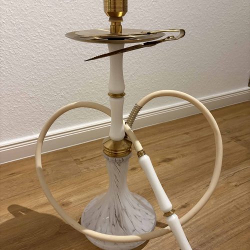 Shisha-Kopf mit Gold-Details und Schlauch auf Holzboden.