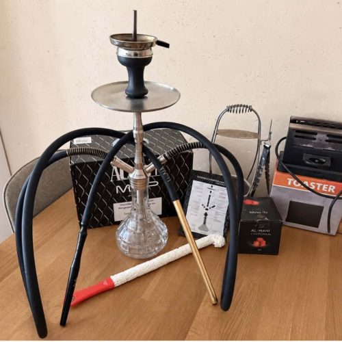 Shisha mit Glasbowl, Kohle und Zubehör auf Tisch.