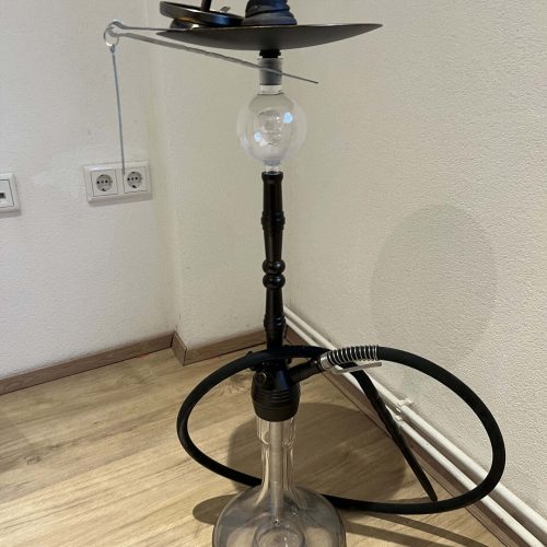 Shisha mit Glasbowl, Schlauch und Kopf, auf Holzboden.