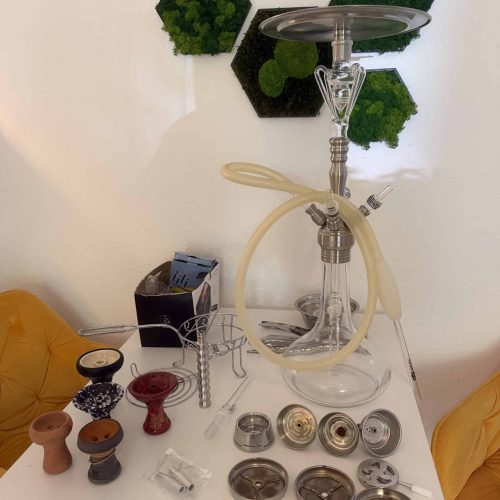 Verschiedene Shisha-Teile und Glasbowl auf Tisch.